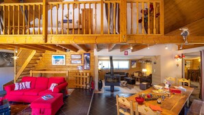 Ein großzügiger Wohnbereich mit rotem Sofa, Holzesstisch und Kamin.