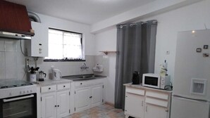 A compact kitchen with white cabinets, a stove, a sink, a microwave, and a refrigerator. - Villa au Bord de Mer (Fontanelas)