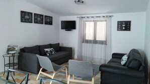 A living room with a sofa, two chairs, a TV, and artwork on the walls. - Villa au Bord de Mer (Fontanelas)