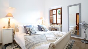 Et pænt opredt soveværelse med seng, sengeborde, skrivebord og et spejl.