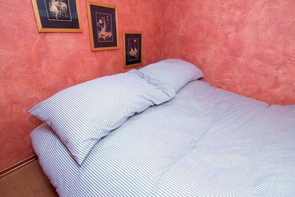 A room with a bed, a pink textured wall, and three framed pictures. - Villa Cyclamino 333 - Villaggio Le Casere (Nevegal)
