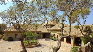 Eine traditionelle Villa im mediterranen Stil mit Innenhof, Steinwegen und ausgereiften Bäumen.