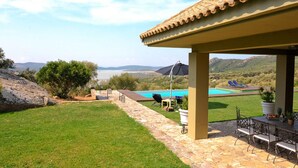Eine Terrasse mit Pool, Gartenmöbeln und Blick auf einen See und Berge.