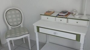 A white desk with a green accent, a chair with a patterned cushion, and a lamp.