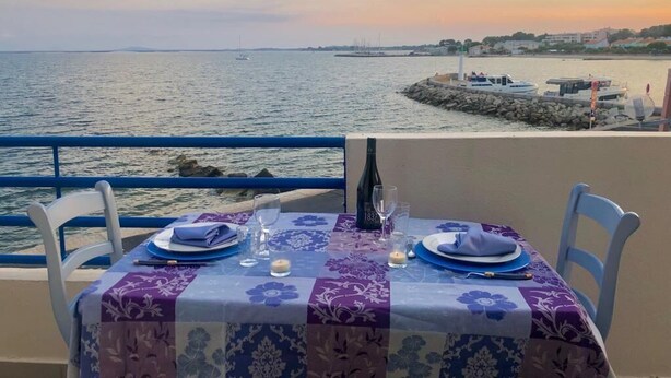 A table set for two with a view of the sea and a distant shoreline.