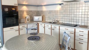 A compact kitchen with a round dining table, built-in oven, microwave, and a gas stove.