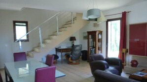 Ein geräumiges Wohnzimmer mit Treppe, einem Essbereich mit Glastisch und einem roten Schrank.