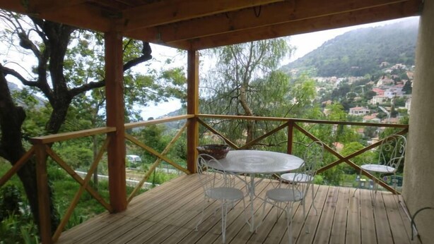 Eine Holzdar Terrasse mit Tisch und Stühlen mit Blick auf eine gebirgige Landschaft.