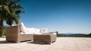 A wicker sofa with white cushions on a patio with a clear view of the mountains. - Panoramic view Grimaud (La Garde-Freinet)