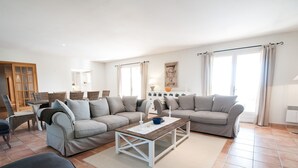 A spacious living room with a grey sofa set, a wooden coffee table, and a dining area with wicker chairs. - Panoramic view Grimaud (La Garde-Freinet)