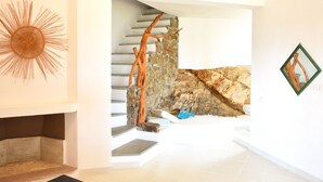 Een modern interieur met een stenen trap, een decoratieve zonachtige muurdecoratie en een lijstwerk met kunst.