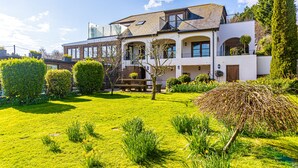 A two-story house with a well-maintained lawn and garden. - Sea View Studio Flat with heated indoor pool & spa, countryside location (Hastings)