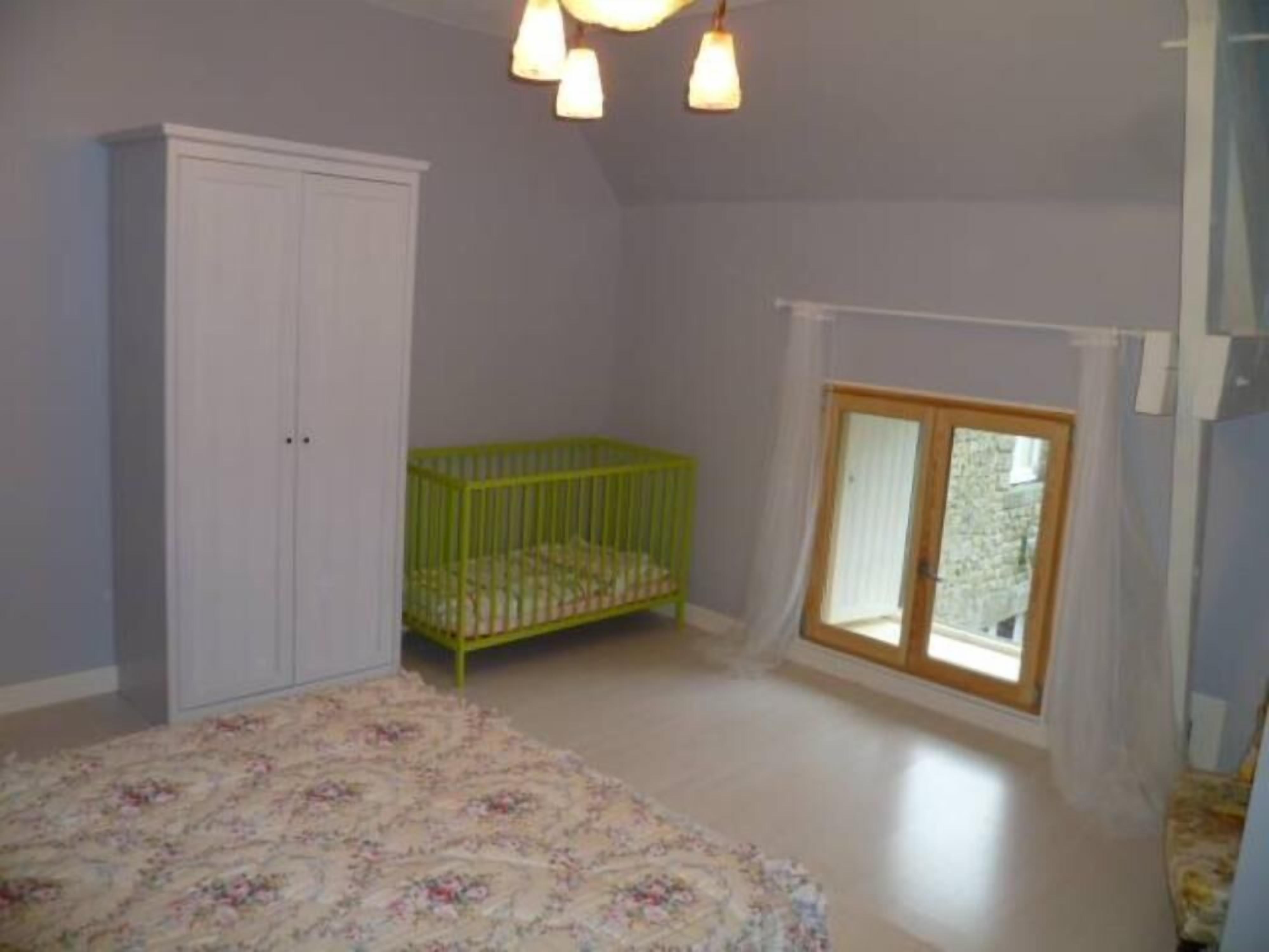 A room with a crib, a wardrobe, and a window with a view.
