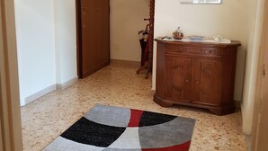 A hallway with a patterned rug, a wooden cabinet, and a door. - Big house near Appia Antica (Roma)