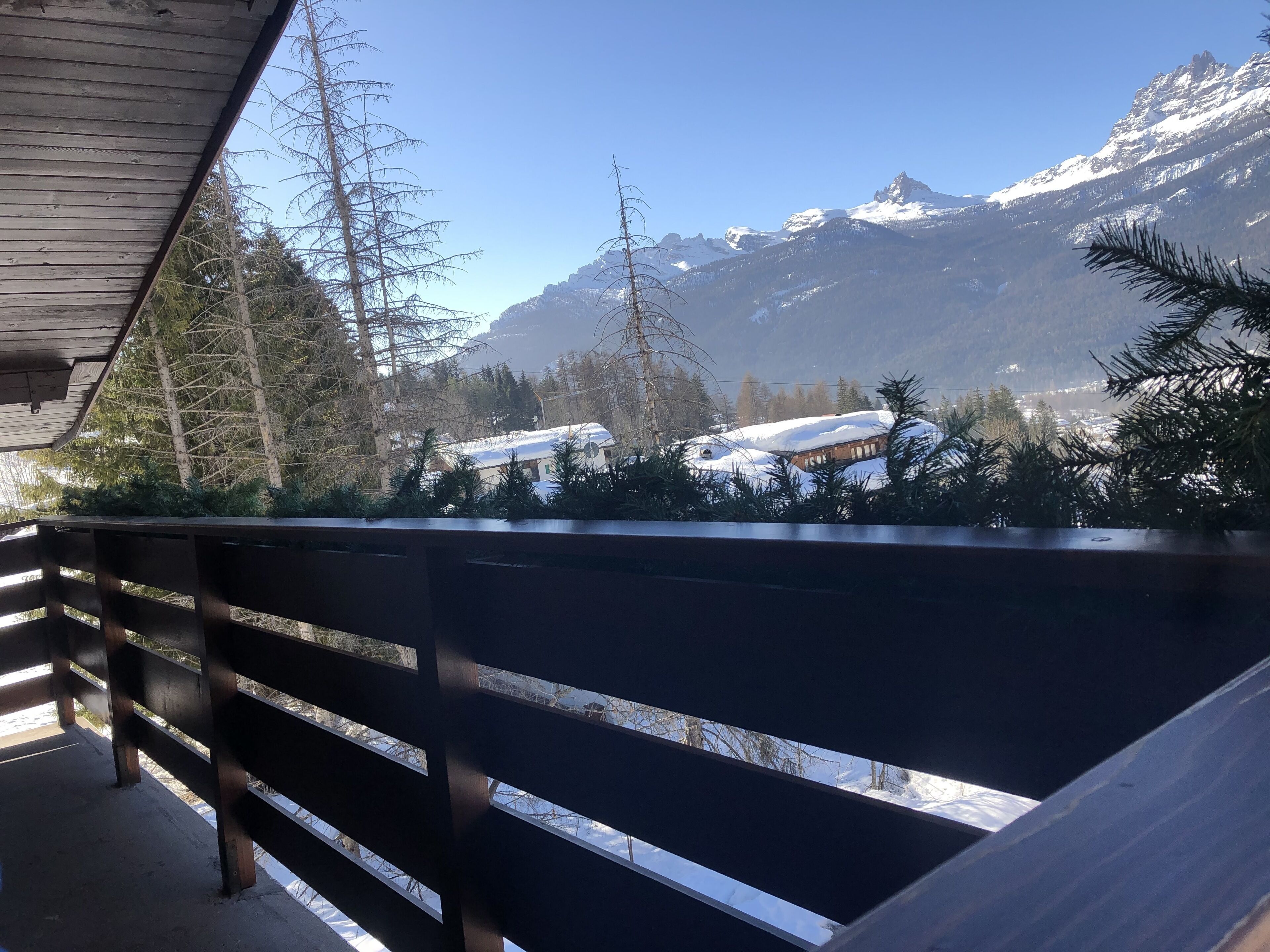 A balcony with a view of snow-covered mountains and a clear sky.