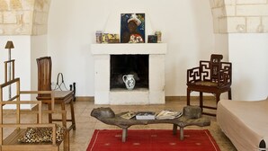 A room with a fireplace, a red rug, wooden furniture, and a stone wall.