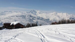 Een berglandschap bedekt met sneeuw, met houten chalets en een heldere lucht.