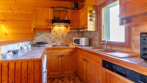 Une cuisine en bois équipée d’un lave-vaisselle, d’un four à micro-ondes et d’une fenêtre donnant sur un paysage agréable.