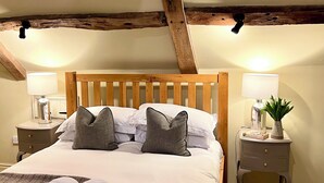 Une chambre à coucher avec un lit en bois, deux tables de chevet, une petite table, une lampe et un vase avec des fleurs.