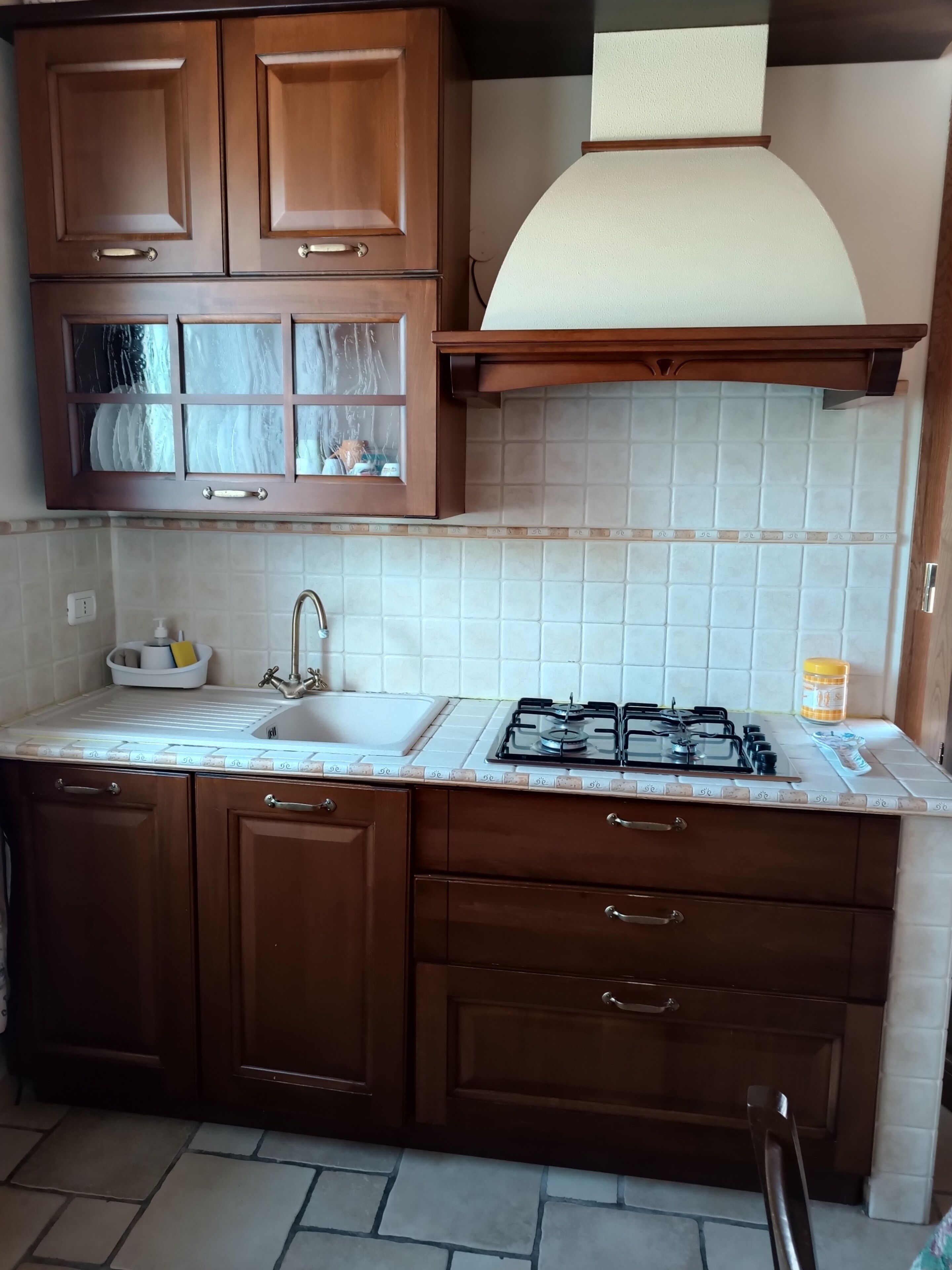 A kitchen with wooden cabinets, a gas stove, a sink, and a tiled backsplash.
