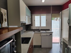 A compact kitchen with a built-in oven, a dishwasher, and a window providing natural light.