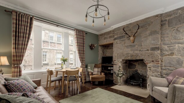 Una sala de estar acogedora con chimenea de piedra, comedor con mesa y sillas, y un sofá cómodo.
