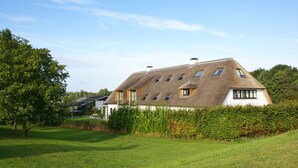 A house with a thatched roof, multiple windows, and a well-maintained lawn. - The ground floor of a beautifully renovated luxury farm! (Erlecom)