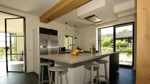 A modern kitchen with a large island, bar stools, and a view of the outdoors. - The ground floor of a beautifully renovated luxury farm! (Erlecom)