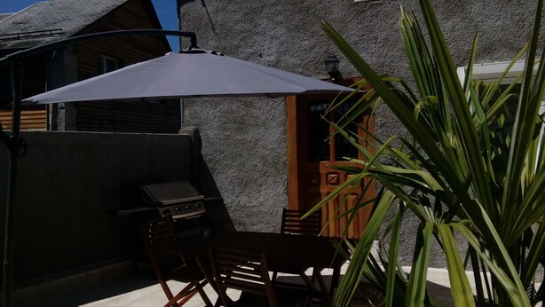 An outdoor patio with a grill, a table, and chairs. - In Marignac, house of 70m2, all comfort, with closed courtyard. (5 people) (Marignac)