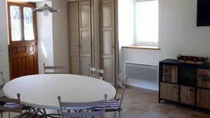 A dining area with a round table and chairs, wooden beams on the ceiling, a window, and a radiator. - In Marignac, house of 70m2, all comfort, with closed courtyard. (5 people) (Marignac)