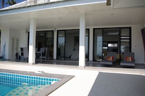 Un hotel modern amb una zona exterior coberta, una piscina i una escala que condueix als pisos superiors.