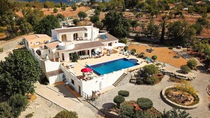 Una villa amplia con piscina, mobiliario de exterior y un jardín ajardinado.