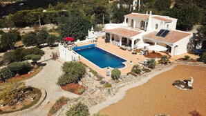 Una villa con piscina, mobiliario de exterior y jardín.