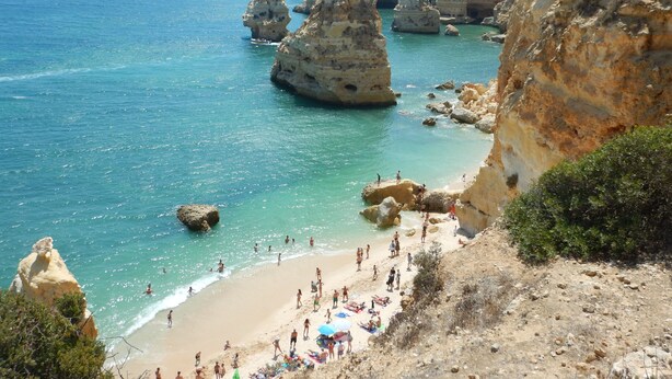 Una playa costera con acantilados rocosos y aguas turquesas cristalinas.