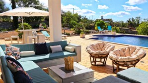 Un área junto a la piscina con sofá, sillas y una mesa.