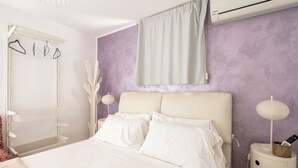 Une chambre à coucher avec un lit, une tête de lit blanche, des tables de chevet et une armoire.