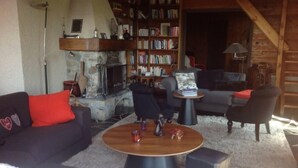 Een knusse woonkamer met een open haard, een boekenplank en comfortabele zitplaatsen.