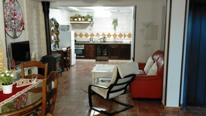 Amplia sala de estar con una mesa de comedor, sillas, un sofá y una cocina al fondo.