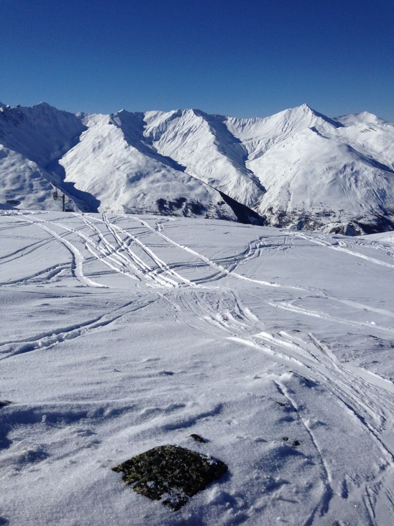Een berglandschap bedekt met sneeuw, met zichtbare ski-sporen.