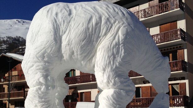 A large snow sculpture in a snowy area with a building in the background. - Very comfortable apartment in the center of the resort- at the foot of the slop (Valloire)