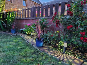Stroll through the serene garden, surrounded by lush greenery and vibrant blooms, leading to a charming wooden deck.
