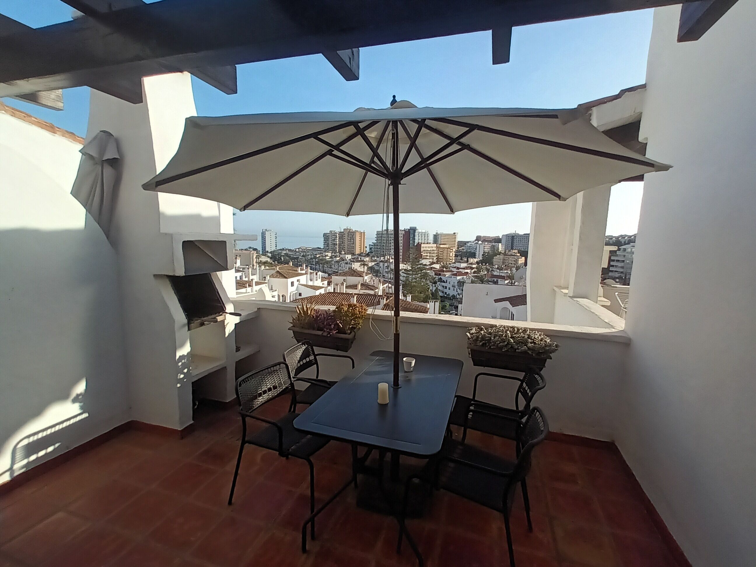 A patio with a table and chairs, an umbrella, and a grill.
