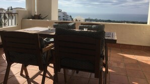 A terrace with a table and chairs, overlooking a coastal view. - Apartment With Fabulous Sea Views, Excellent Facilities, Heated Indoor Pool (malaga)
