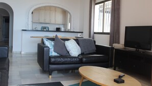 A modern living room with a black leather sofa, a wooden coffee table, and a flat-screen TV. - Apartment With Fabulous Sea Views, Excellent Facilities, Heated Indoor Pool (malaga)