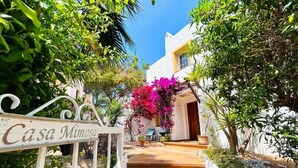 A pathway leading to a white building with a sign reading "Casa Mimosa."