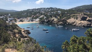 A coastal town with a beach, boats, and buildings on a hillside.