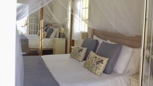A bedroom with a canopy bed, a bedside table, and a mirror.