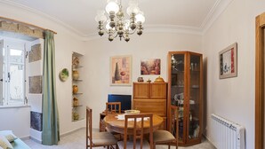 Zona pranzo con tavolo rotondo in legno, sedie, un lampadario e un mobile con ante in vetro.