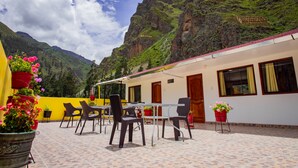 En terrasse med udendørs siddepladser og plantekasser, med udsigt over et bjergrigt landskab.