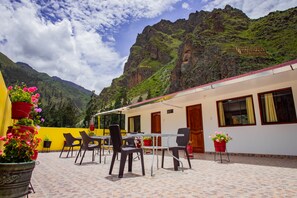 A terrace with outdoor seating and potted plants, overlooking a mountainous landscape. - Hotel with two terraces overlooking the mountains and the temple of the Inca sun (OLLANTAYTAMBO)